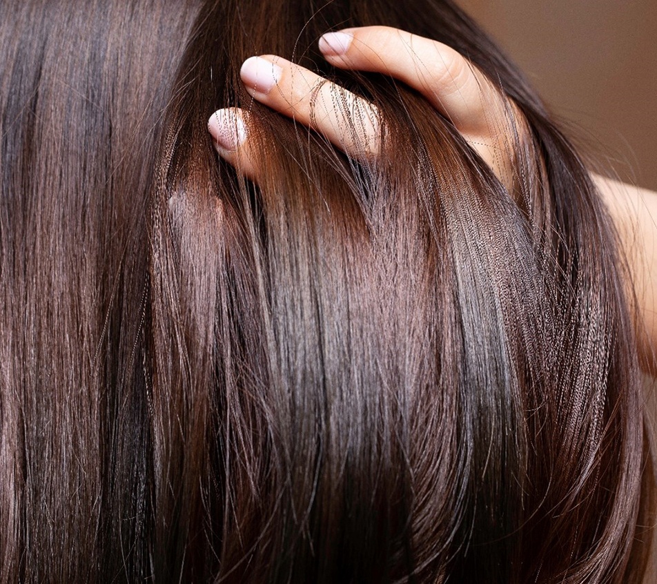 Woman running fingers through healthy hair after Keravive HydraFacial treatment