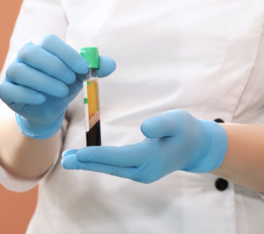 Gloved hands holding tube of blood